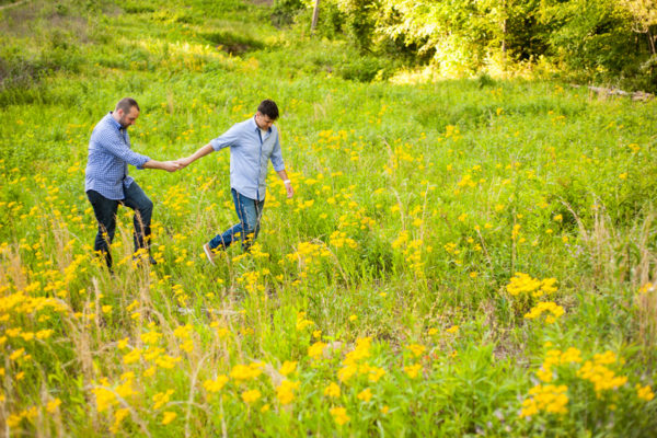 gay couple backyard engagement session field yellow flowers