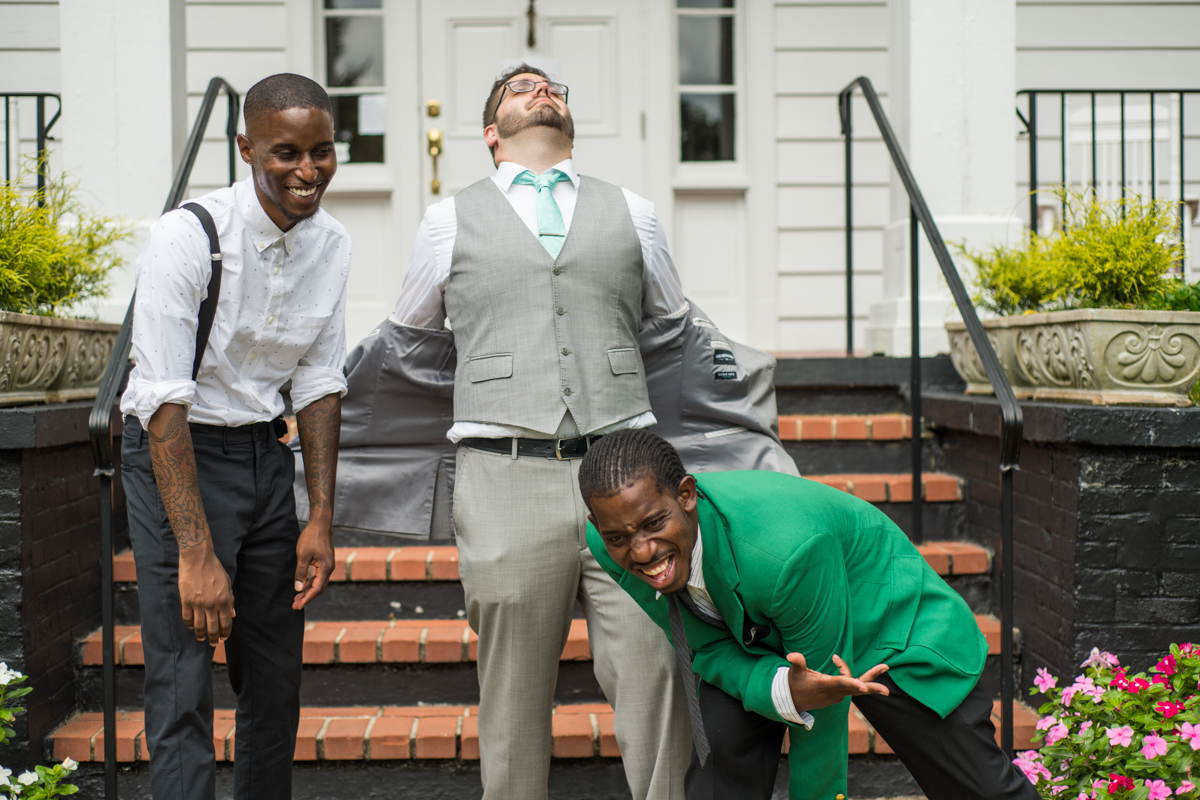 groom laughs with groomsmen during portraits