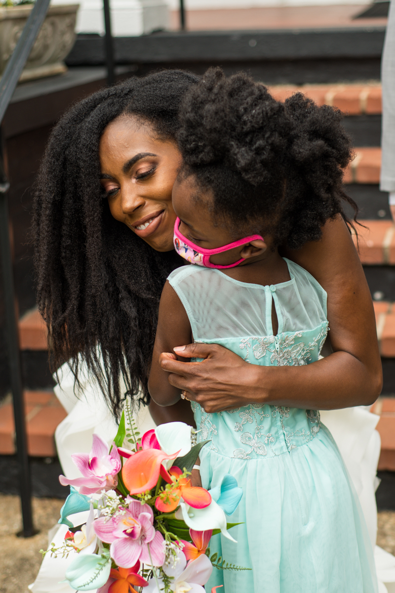 bride hugs flower girl during outdoor wedding in COVID19 pandemic